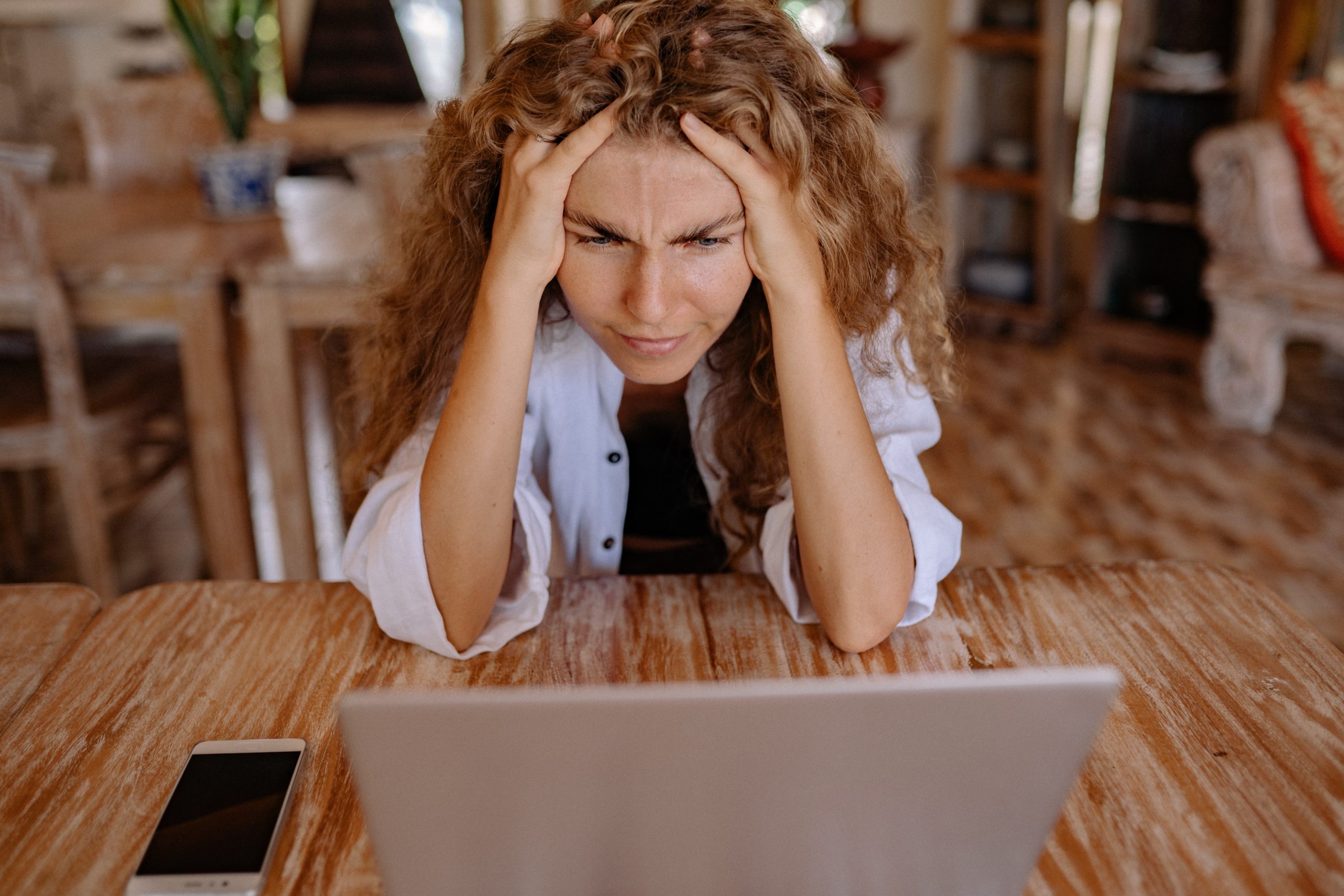 Woman frustrated with her hands in her hair as she looks frustrated at her laptop