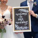 Married couple holding a sign that says Welcome to our Wedding