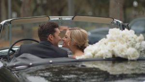 Bride and groom kissing in car