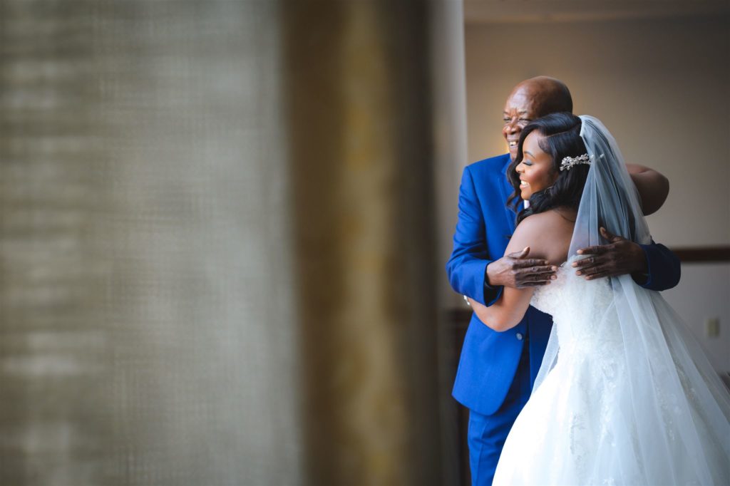 Father of the bride hugging his daughter at a Haitian wedding.