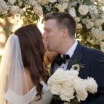 Married couple kissing under flower arch at Lake Nona Country Club