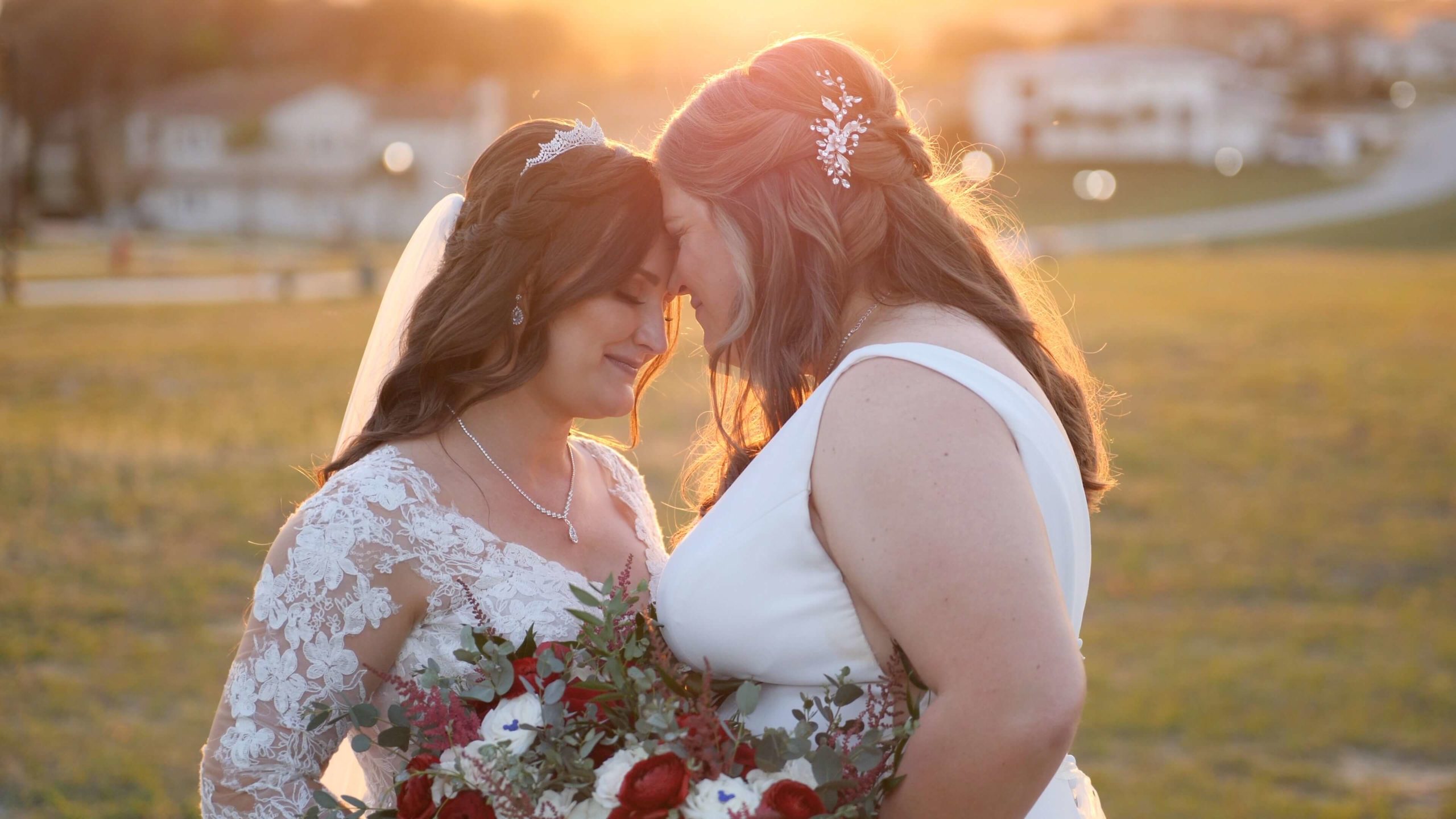 Brides touching foreheads at sunset at their lesbian wedding
