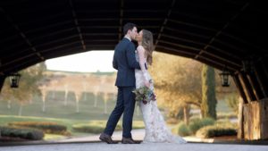 Bride and groom kissing under the bridge at The Club at Bella Collina
